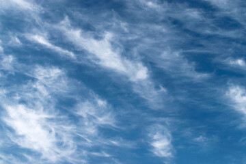 White feathery fluffy clouds on a blue sky, background and texture