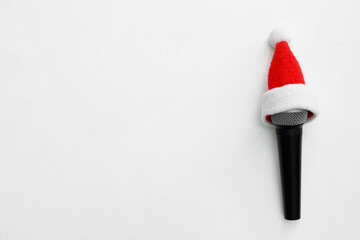 Top view of microphone with Santa hat on white table, space for text. Christmas music
