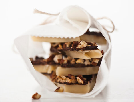 Toffee with chocolate and nuts, stacked and wrapped in parchment