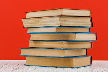 A stack of books on a white table on a red background