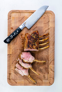 Rack of lamb on a cutting board with a knife
