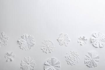 Many paper snowflakes on white background, flat lay. Space for text