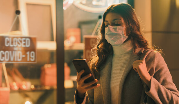Shop closed due to coronavirus outbreak and woman connecting with her smartphone
