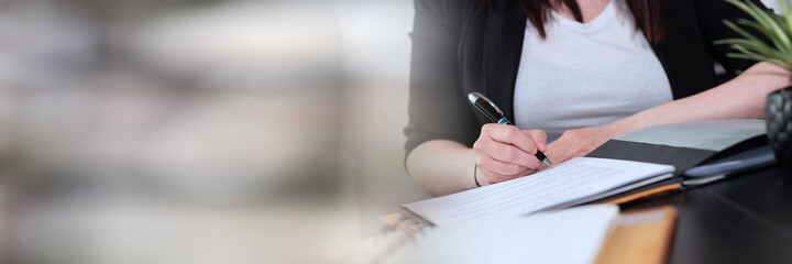 Businesswoman signing a document; panoramic banner