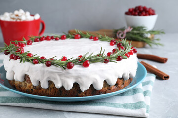 Obraz na płótnie Canvas Traditional Christmas cake decorated with rosemary and cranberries on light grey marble table, closeup