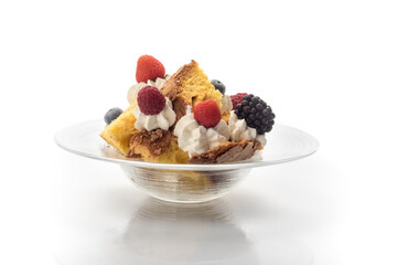 Panettone in pieces with cream, strawberries, raspberries, blackberries and raisins. Italian dessert for Christmas in the plate on white background