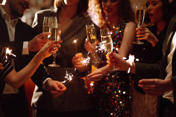 Sparkling sparklers in the hand. Group of happy people holding sparklers at the party. Young...