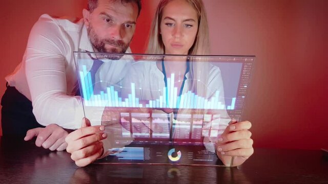 Male and Female Looking at Transparent Futuristic Tablet With Business Charts.  Motion Graphics, Future Technology Concept, Static Full Frame