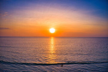 Aerial drone view Beautiful sunset over the clam sea with cloud and sky background. Sunset over tropical beach. Nature summer  concept. Peak sunset over sea with yellow light reflect in cloud.