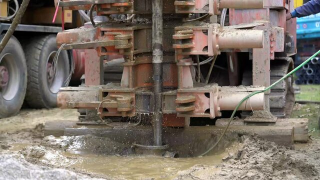a truck with a drill makes a well and throws muddy water out of the hole
