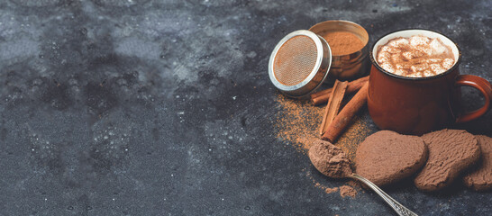 Obraz na płótnie Canvas Hot chocolate (cocoa) drink banner backround. Cocoa drink on a dark background with cinnamon and whipping. Winter hot drinks