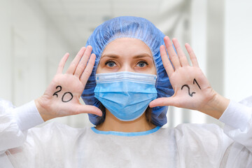 A female doctor in a protective cap and face mask in safety measures against the coronavirus in...