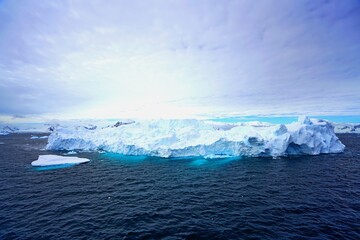 Fototapeta na wymiar Summer landscape in Antarctica with melting snow, sea, icebergs, white clouds.