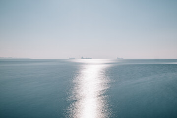 seascape of aegean sea with a faint hazy tanker ship boat in the horizon. blue sky no clouds with...