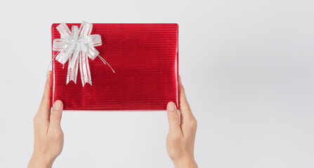 Hand is holding present or Gift box wrap with red color paper on white background.