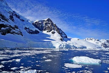 Summer landscape in Antarctica with melting snow, sea, icebergs.