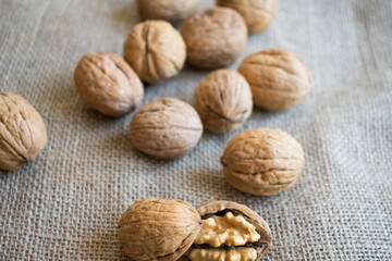cracked walnuts and whole walnuts on brown cloth.