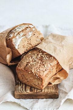 Two loaves of rye bread in paper bags on a wooden board