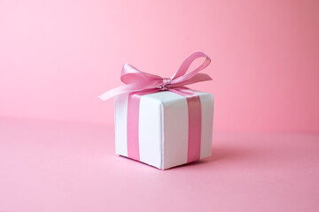 Gift or present box with shiny balls, ribbons and snowflakes on pink background. Flat lay composition for christmas, female Christmas. White gift with pink ribbons. A gift box isolated on pink 