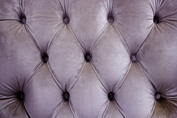 The back of the Chesterfield sofa is made of lavender velour. Decoration with buttons. Three-dimensional carriage screed. Selective focus.