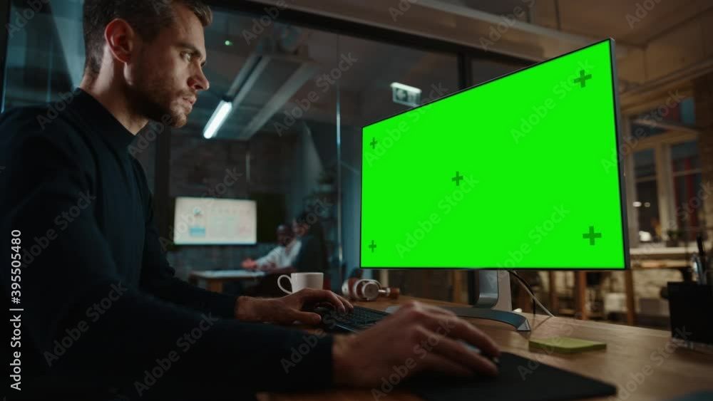 Aufkleber Young Handsome Specialist Working on Desktop Computer with Green Screen Mock Up Display in a Busy Creative Office with Colleagues. Male Manager with Trimmed Beard is Wearing a Casual Black Jumper.