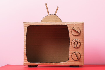 Blank cardboard TV on a pink background. Concept on the topic of television