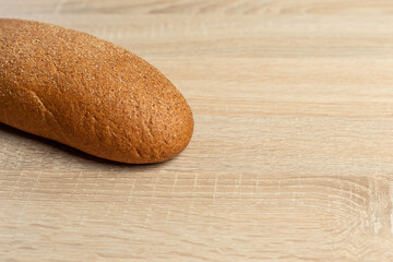Freshly baked traditional black bread on a wooden table. brown coarse bread made from shenitsa, barley, rye flour.