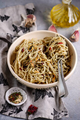 Spaghetti alio olio in a ceramic bowl on a background of concrete.