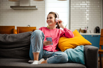 Nice joyful girl listening music with headphones and cellphone