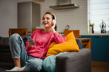 Obraz premium Nice joyful girl listening music with headphones and cellphone