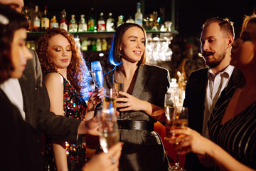 Group of happy people holding sparklers at the party. Young friends clinking glasses of champagne and enjoying new years eve with fireworks. Party, celebration, holidays concept.