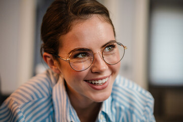 Beautiful happy girl in eyeglasses smiling and looking aside