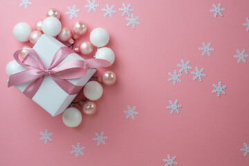 Fototapeta na wymiar Gift or present box with shiny balls, ribbons and snowflakes on pink background. Flat lay composition for christmas, female Christmas. White gift with pink ribbons. A gift box isolated on pink 