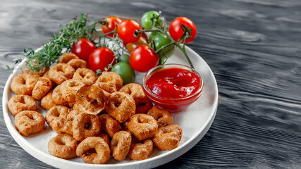 handmade tarallini with tomatoes and herbs is called taralli or TARALLINI. Produced in Italian bakeries in the South of Italy. Small snack rings on a wooden background