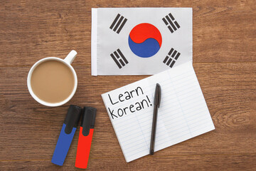 south korea national flag, cup of coffee, two markers, notebook with learn korean inscription on...