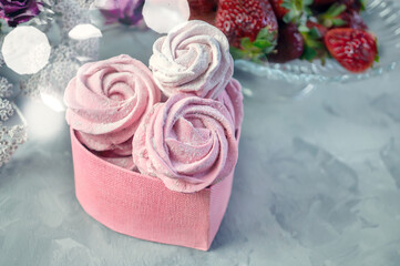 fresh handmade marshmallows in a light mood. Close-up of a pink marshmallow in a pink heart-shaped gift box.Fruit marshmallows with fresh strawberries. Copy space