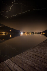 Fulmini sul lago di notte con riflesso 