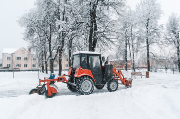 clearing roads from snow. Red excavator cleans the tracks from snow in a Blizzard. Snow drifts on...