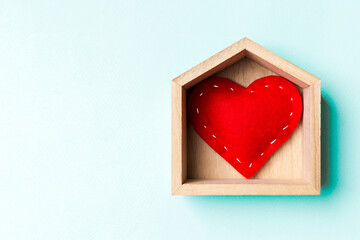 Top view of red textile heart in a wooden house on colorful background. Home sweet home concept. Valentine's day