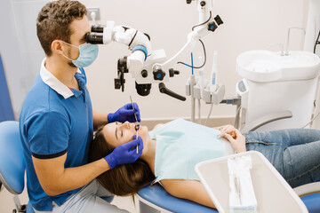 A dentist looking to the microscope at the patient's teeth