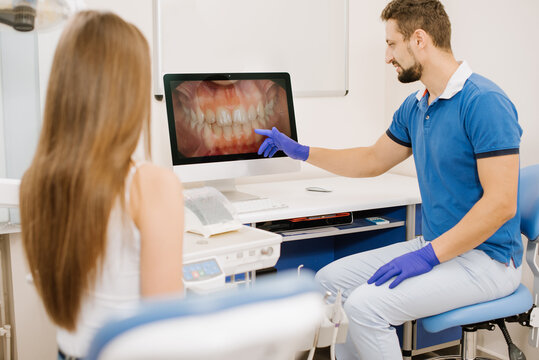 A dentist showing  photo of teeth to the patient on screen