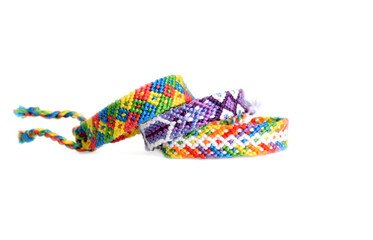 Selective focus of tied woven friendship bracelets with bright colorful patterns handmade of thread isolated on white background