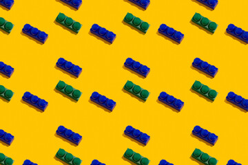 Seamless regular pattern with blocks from the children's constructor on a yellow background. Father and childhood day holiday concept.