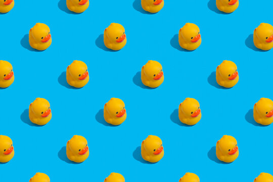 Seamless regular pattern with yellow ducks on a blue background. The concept of games in the bathroom and summer vacation.