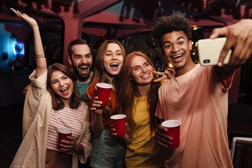 Smiling friends with smartphone taking selfie