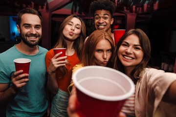 Smiling friends with smartphone taking selfie