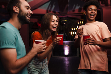 Group of happy young friends celebrating in the nightclub, dancing, drinking