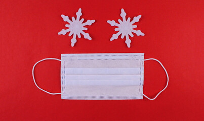 Medical protective mask with two white snowflakes on a red background. Face made of snowflakes and mask