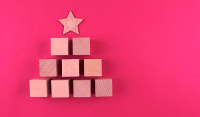 Wooden christmas tree with wooden star on pink background