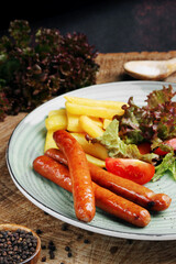 sausages with french fries and salad on wooden table closeup.